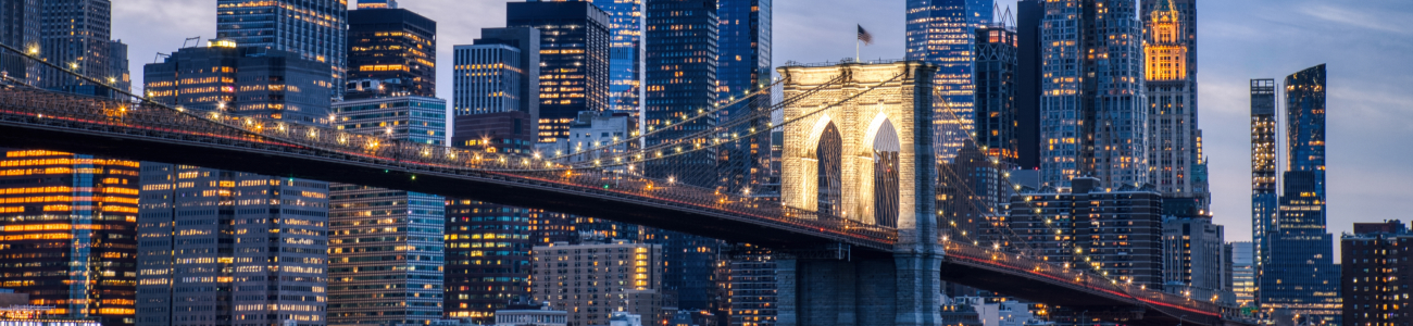 The Brooklyn Bridge spans New York Harbor, connecting Manhattan to Brooklyn.